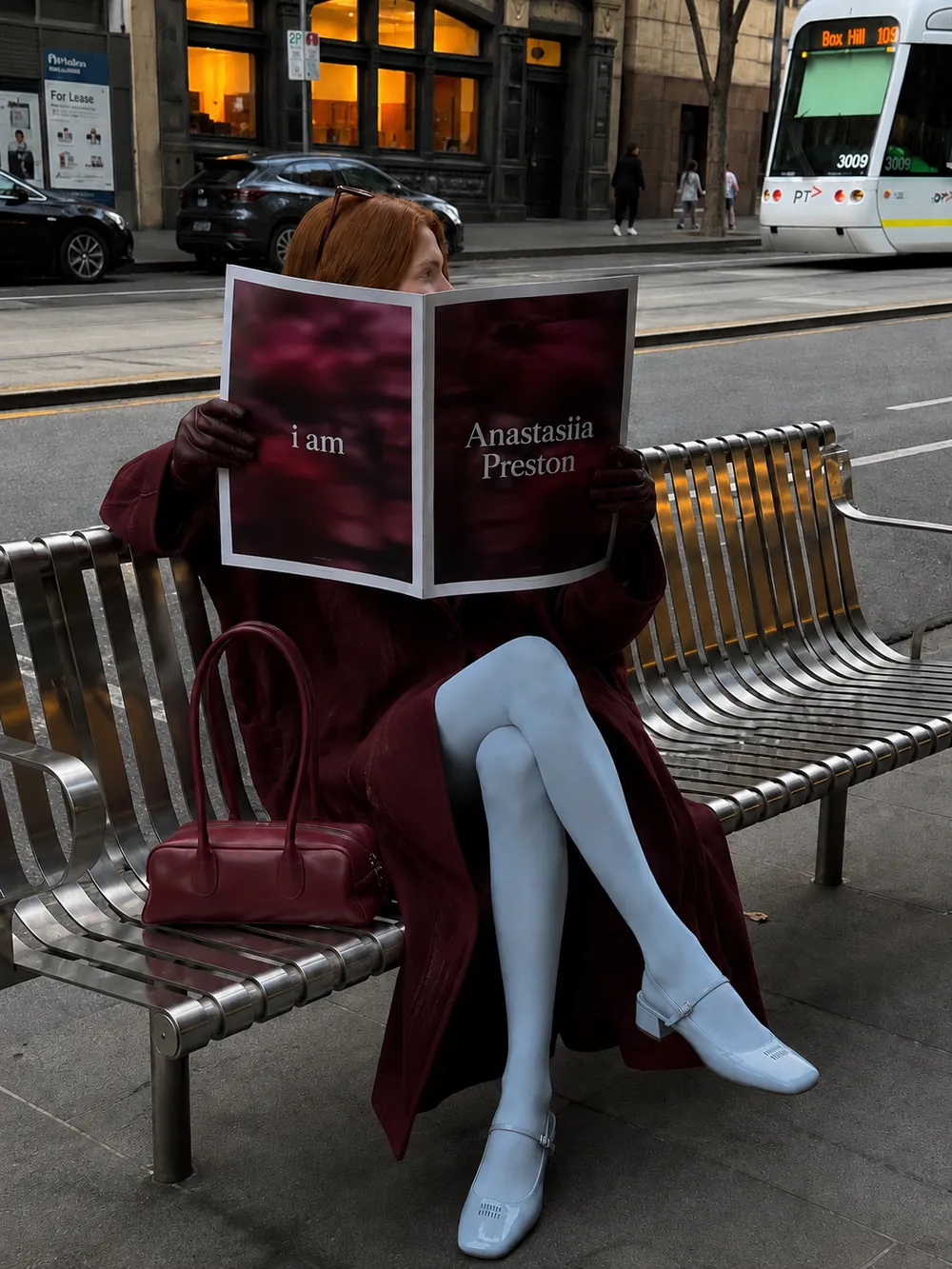 Anastasiia Preston sitting on a bench reading a magazine titled I am Anastasiia Preston